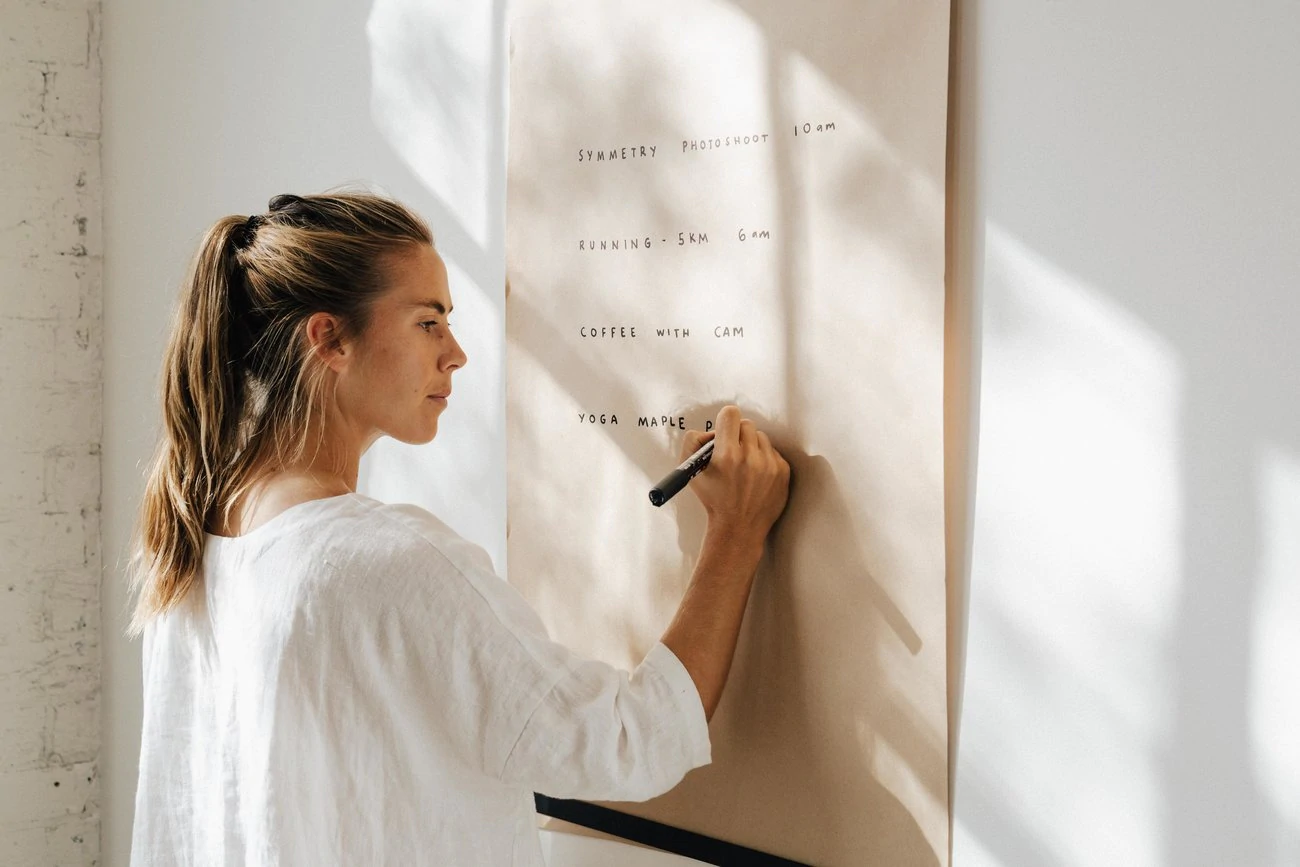 Une femme écrit sur un grand rouleau de papier fixé au mur