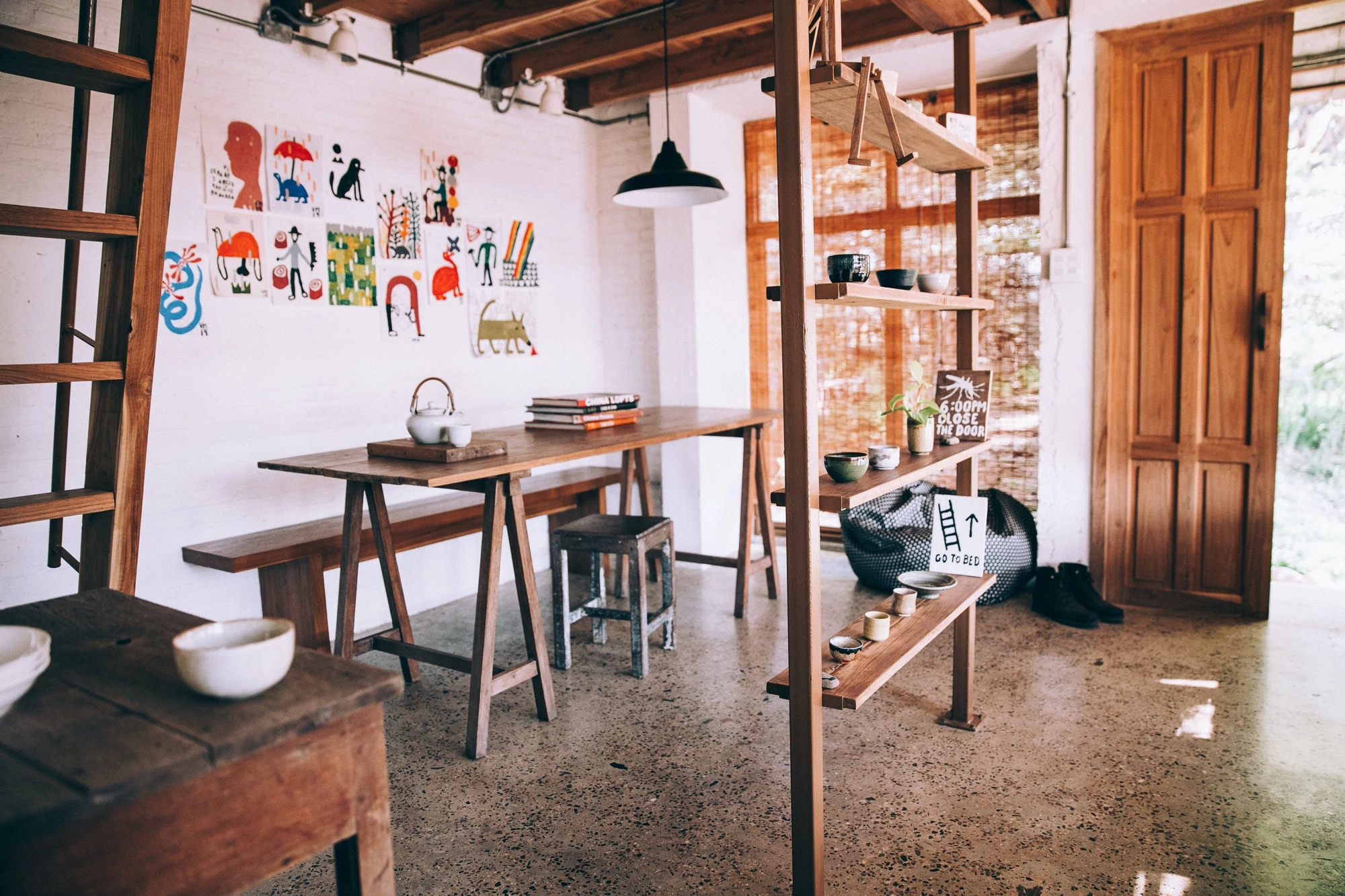 Minimalist room with white walls and wood detailing, colourful art on the walls