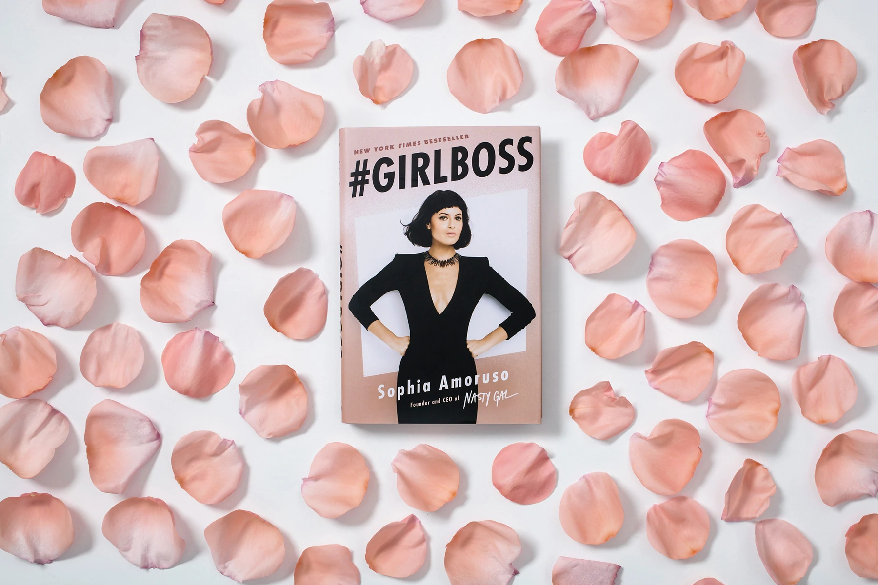 #Girlboss, un libro di Sophia Amoruso, circondato da petali di rose rosa.