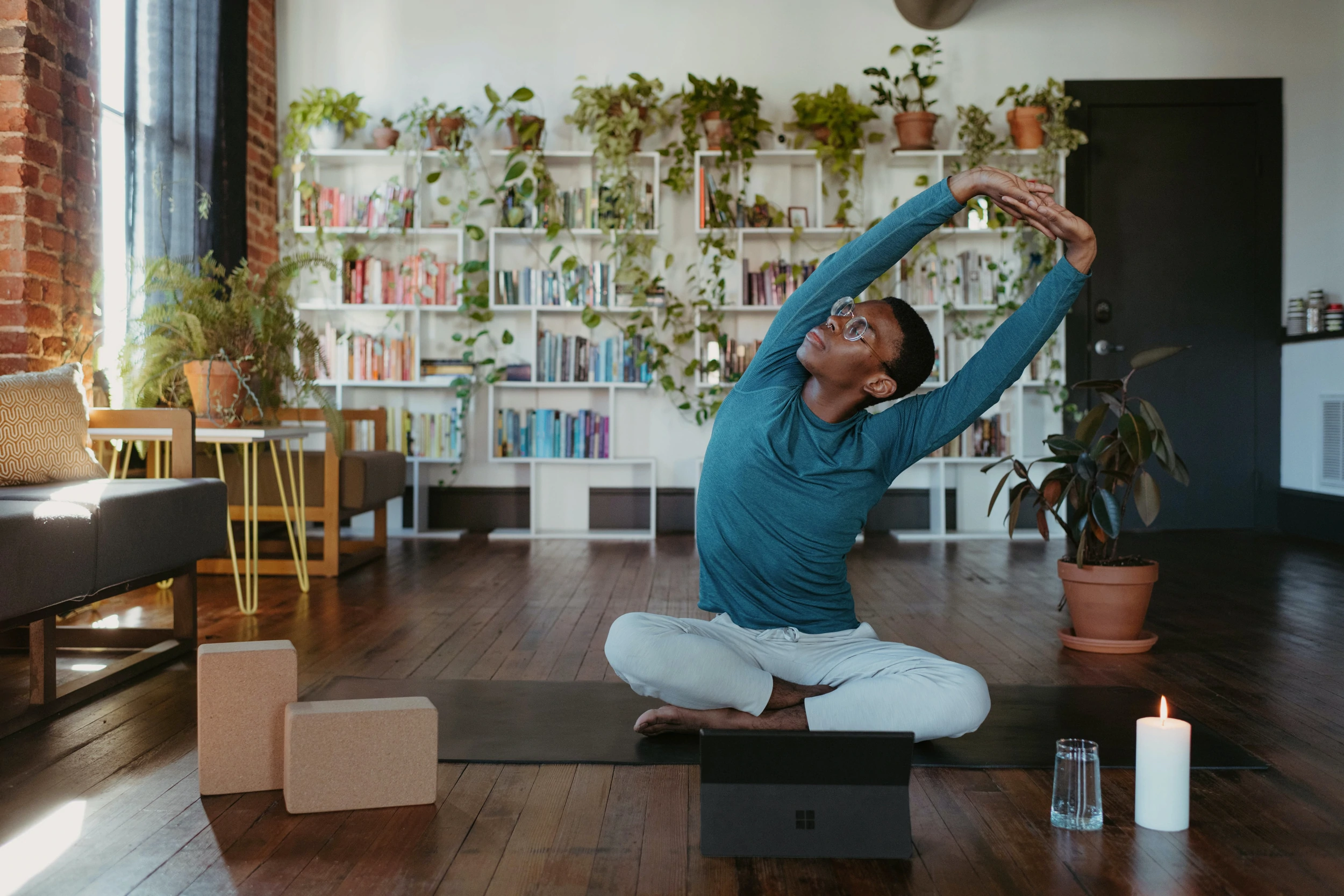 Une personne est assise sur un tapis de yoga et s'étire doucement dans un salon