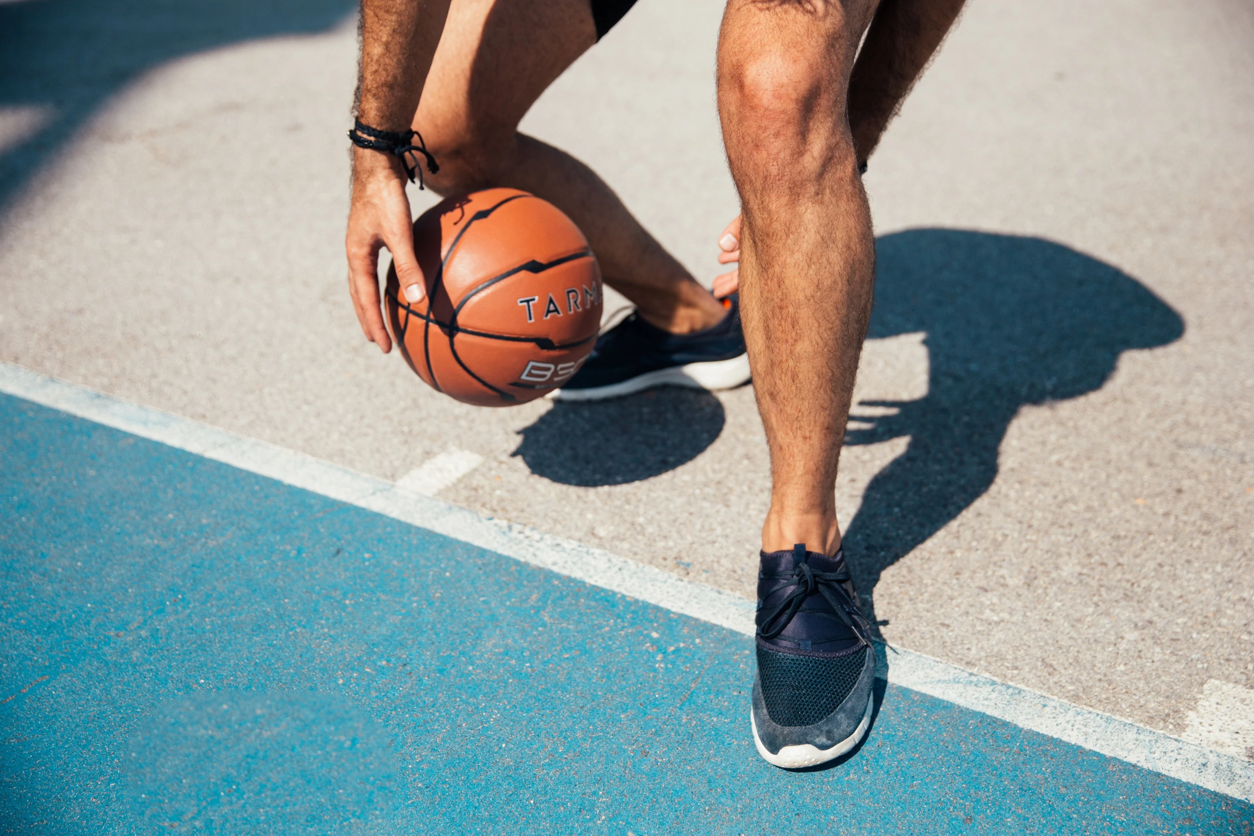 Culture d'une personne sous la taille dribblant un ballon de basket