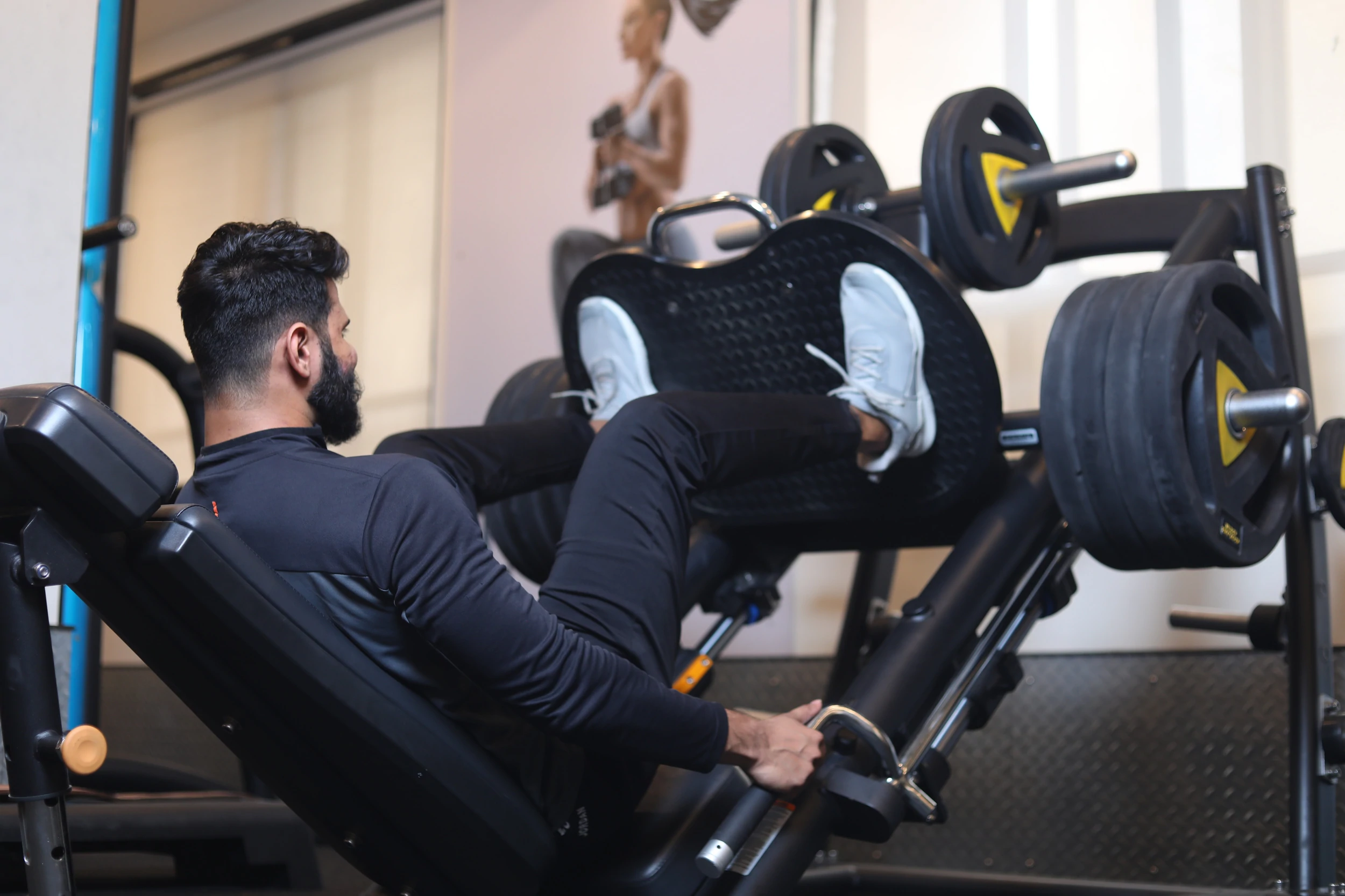 La personne utilise une machine d'haltérophilie pour faire une presse de cuisse