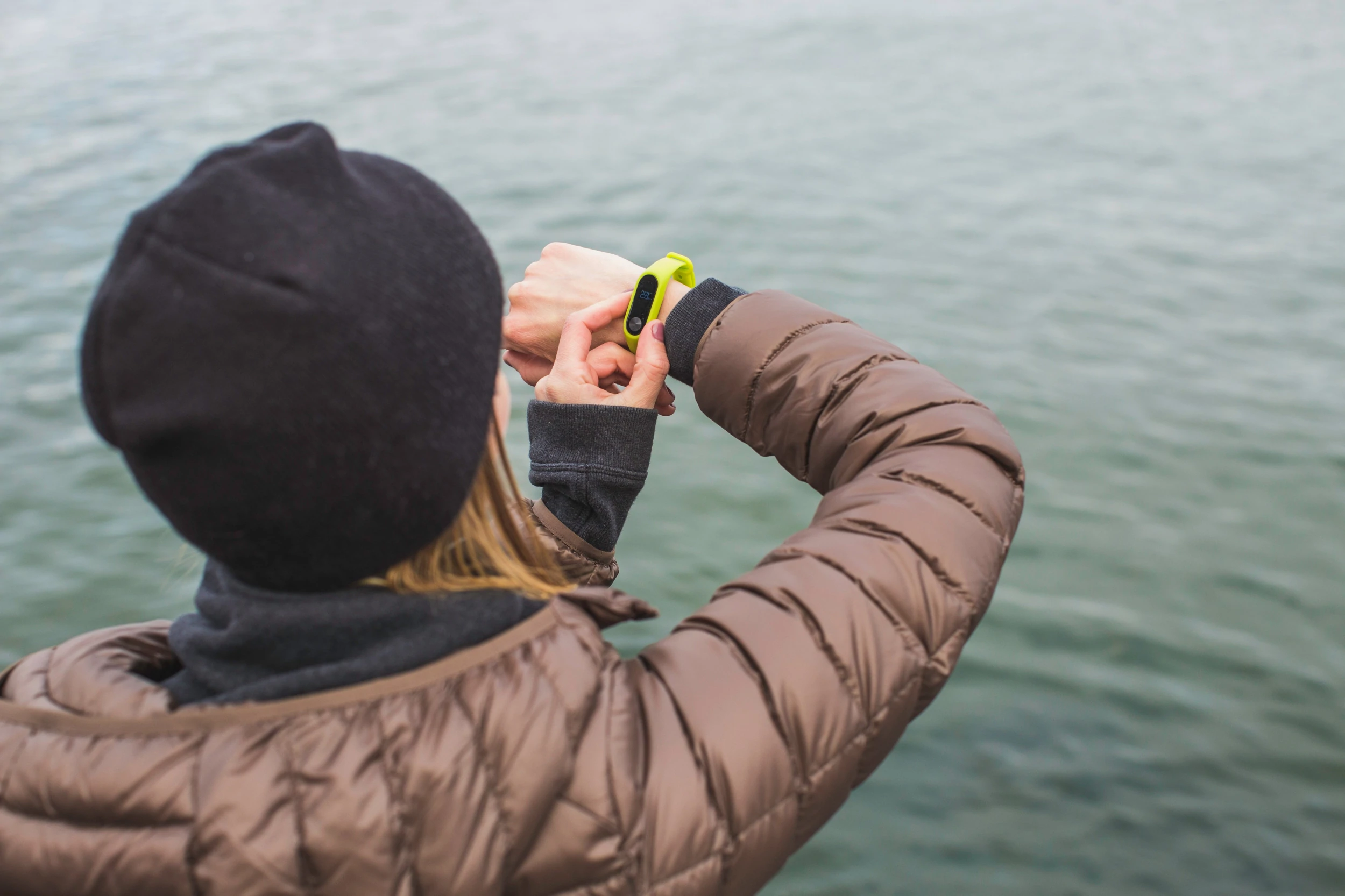 Une personne regarde à travers un plan d'eau et ajuste son tracker de fitness de montre intelligente