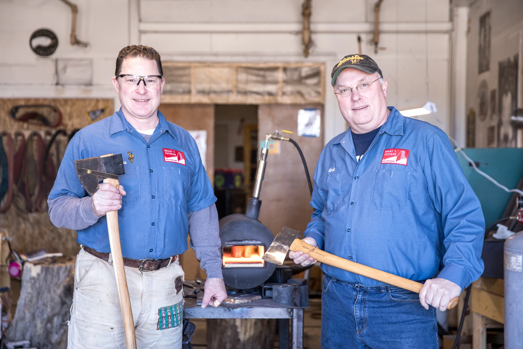 Les fondateurs de Brant & Cochran, Barry Worthing et Mark Ferguson, tiennent des haches dans leur atelier de Portland, dans le Maine.