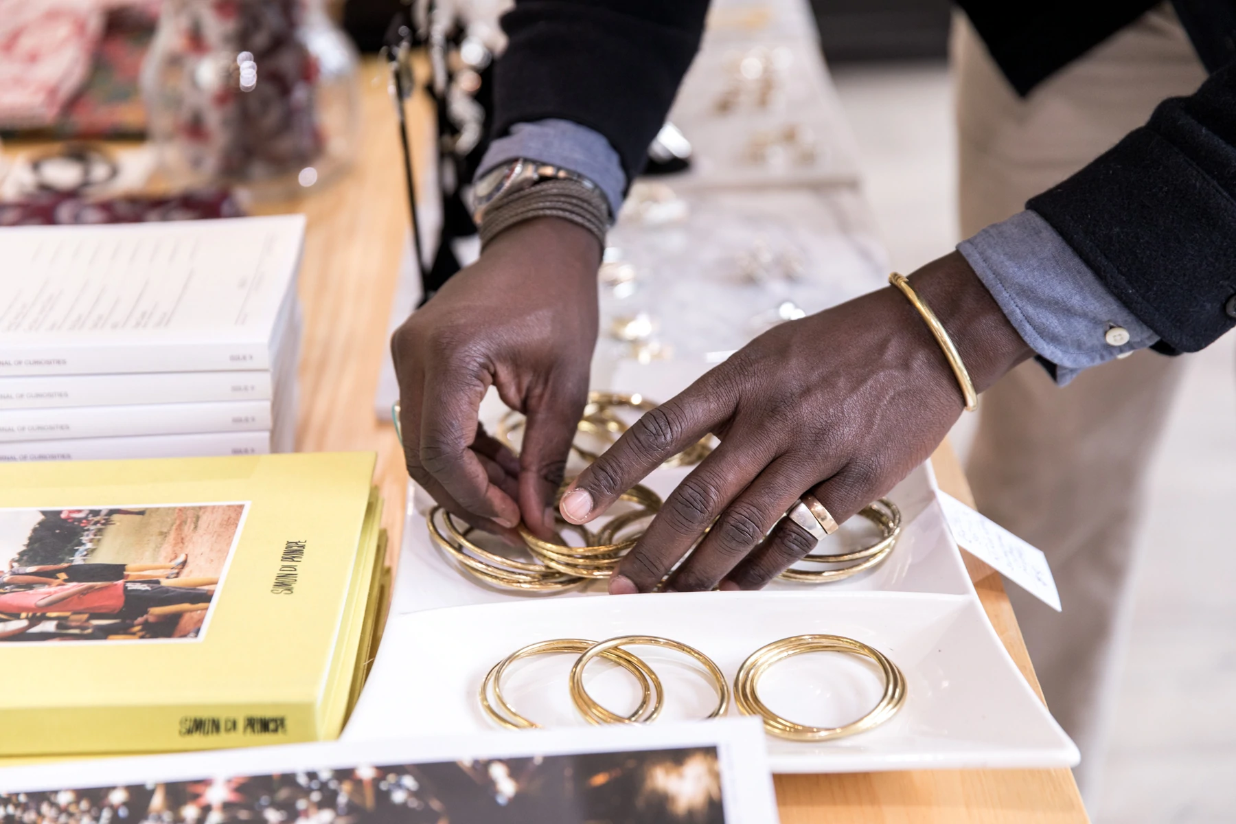 Détail des mains d'un homme arrangeant des bracelets en or sur une table dans un présentoir de vente au détail.