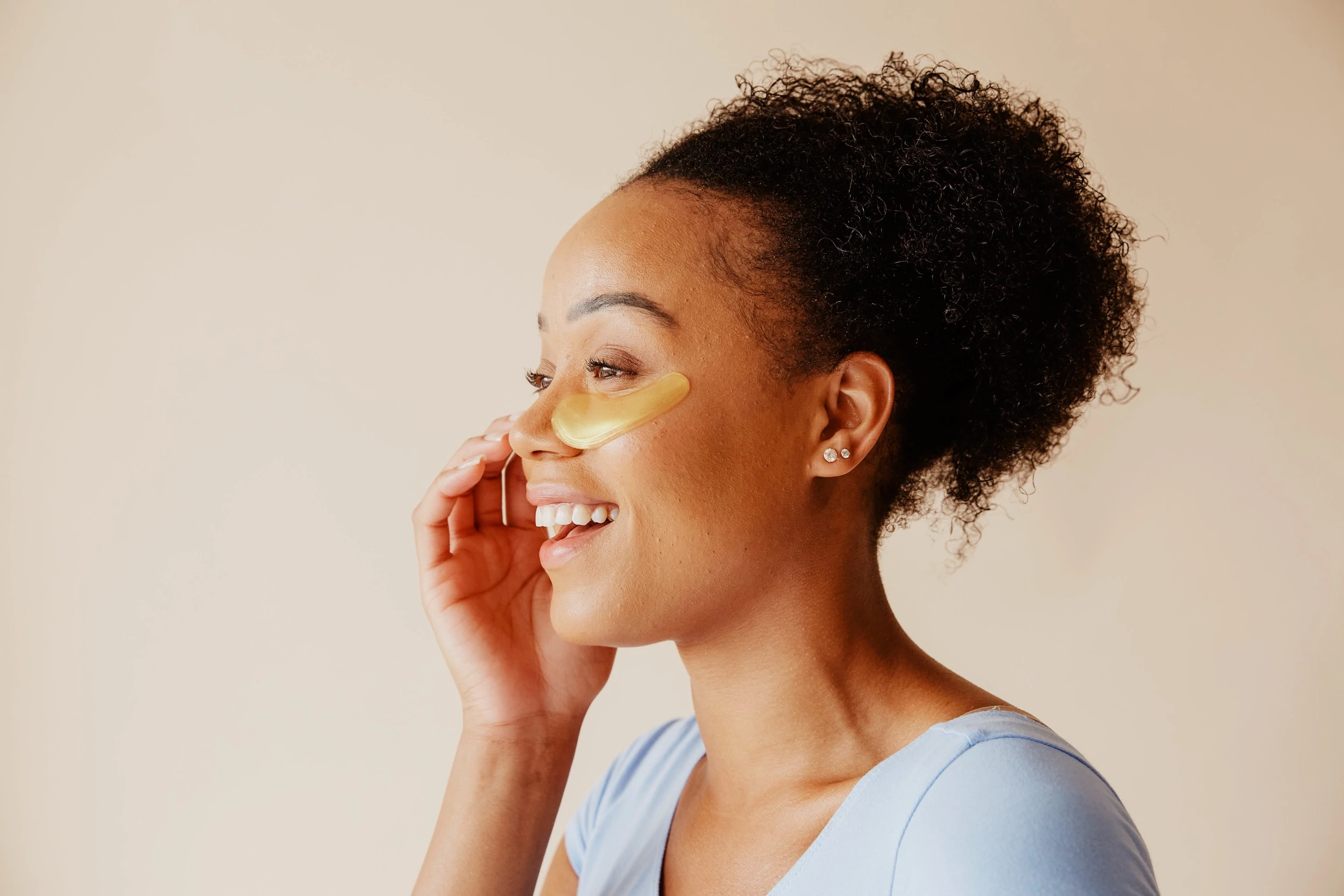 Una donna sorridente usa un prodotto per la cura della pelle con maschera per gli occhi