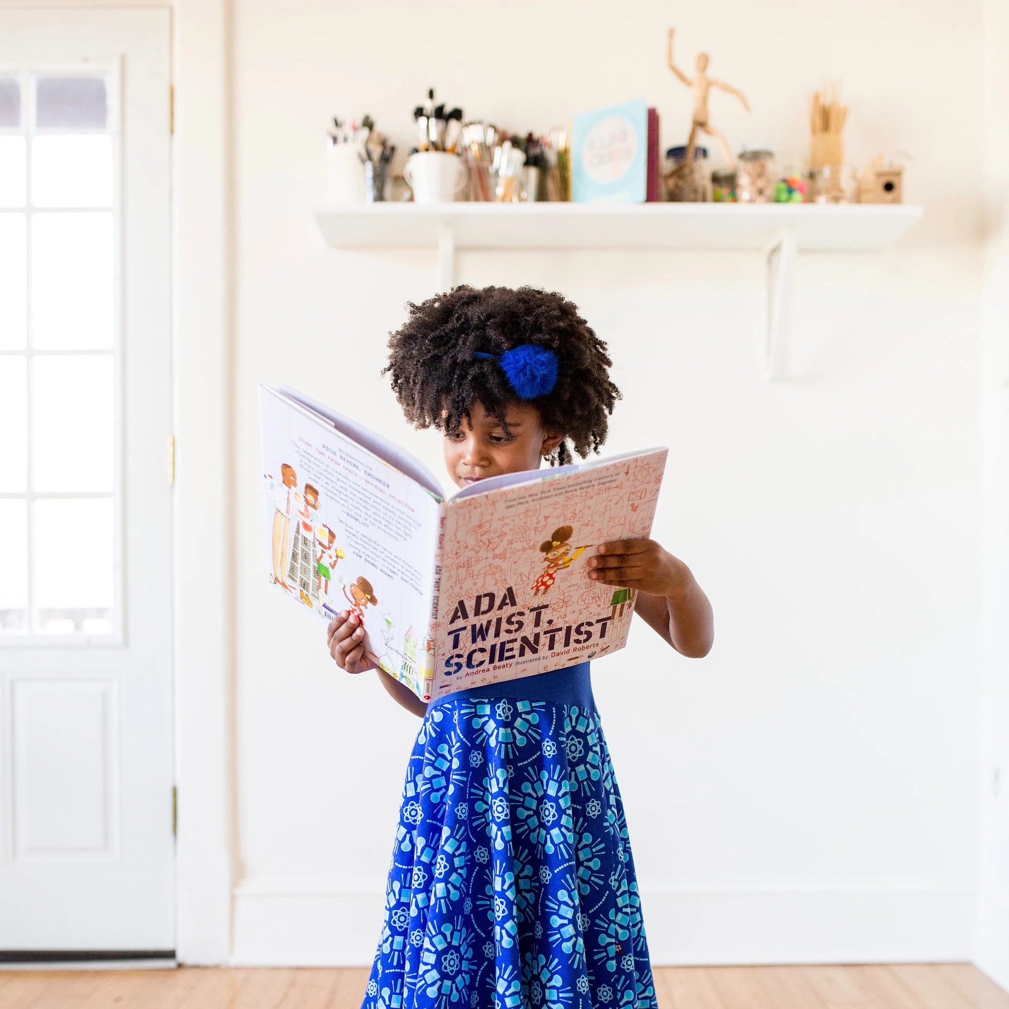 A menina modela um vestido azul da Princess Awesome.