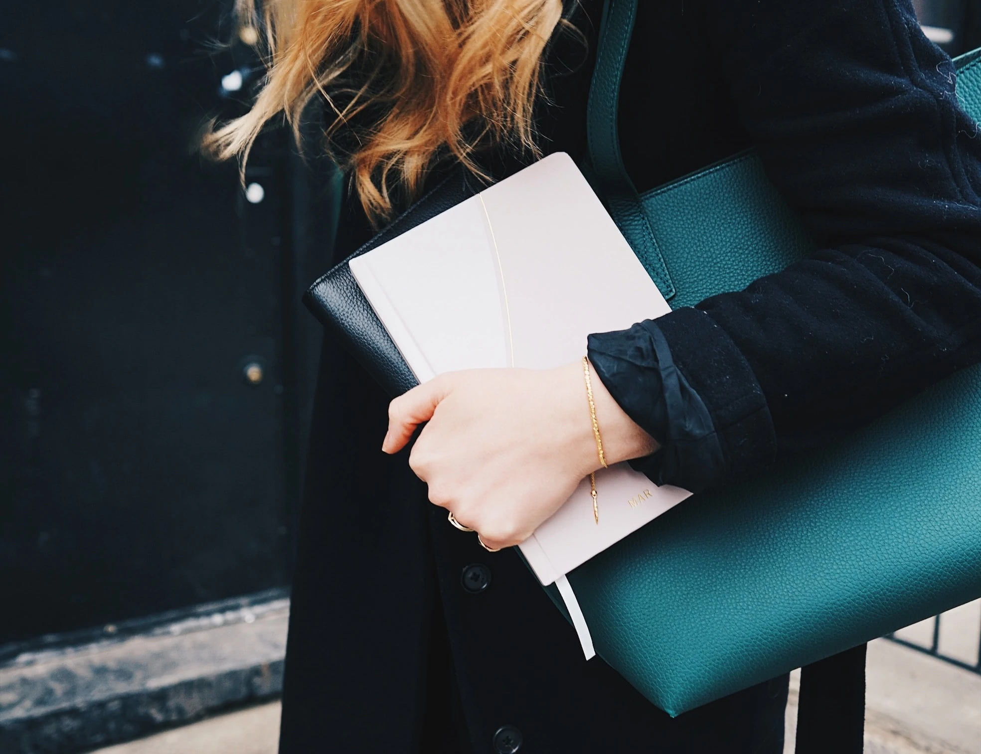 Une personne porte un bloc-notes et un grand sac à main en cuir