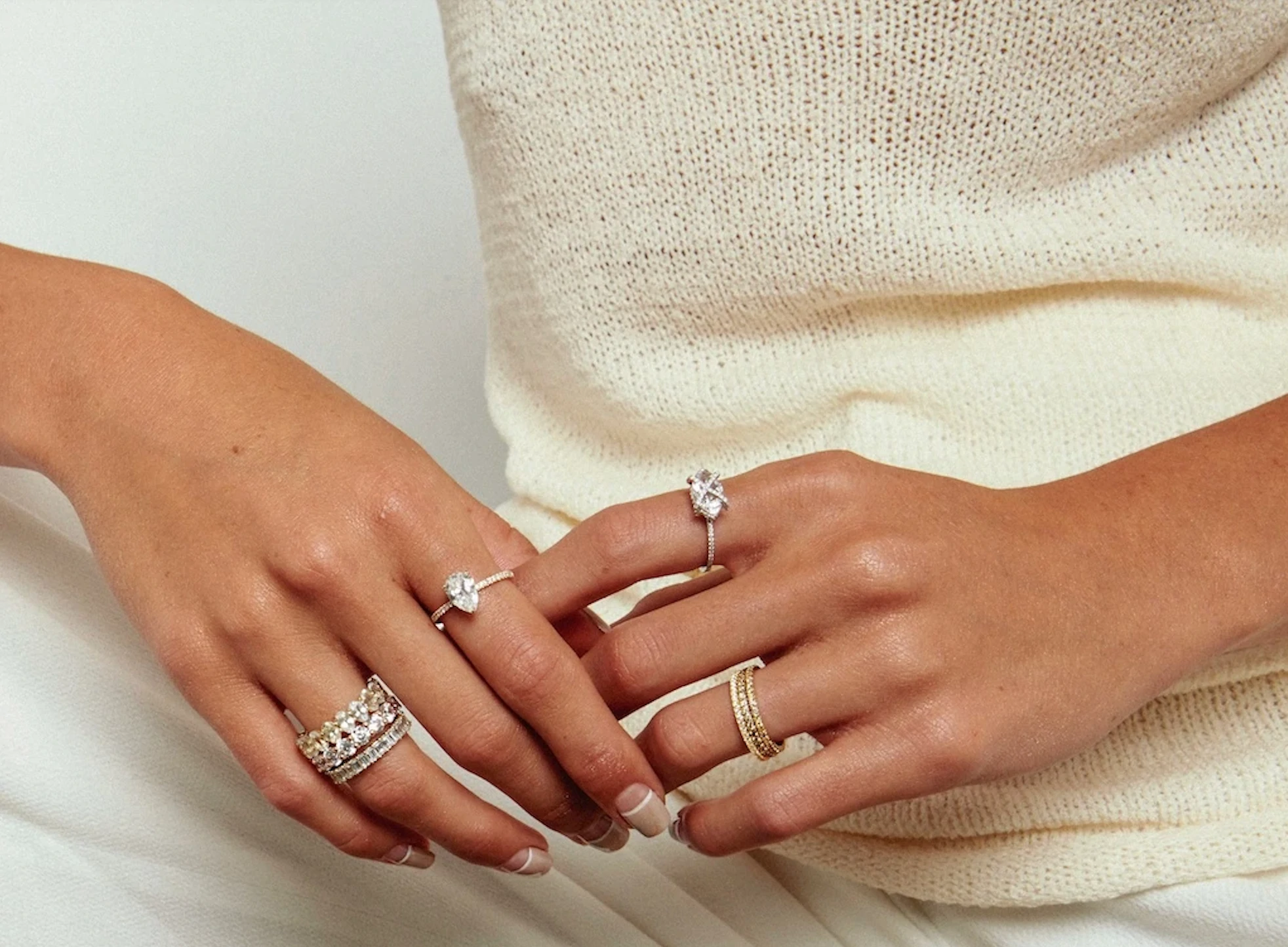 Un gros plan d'une femme portant plusieurs bagues Apres Jewelry sur les deux mains.