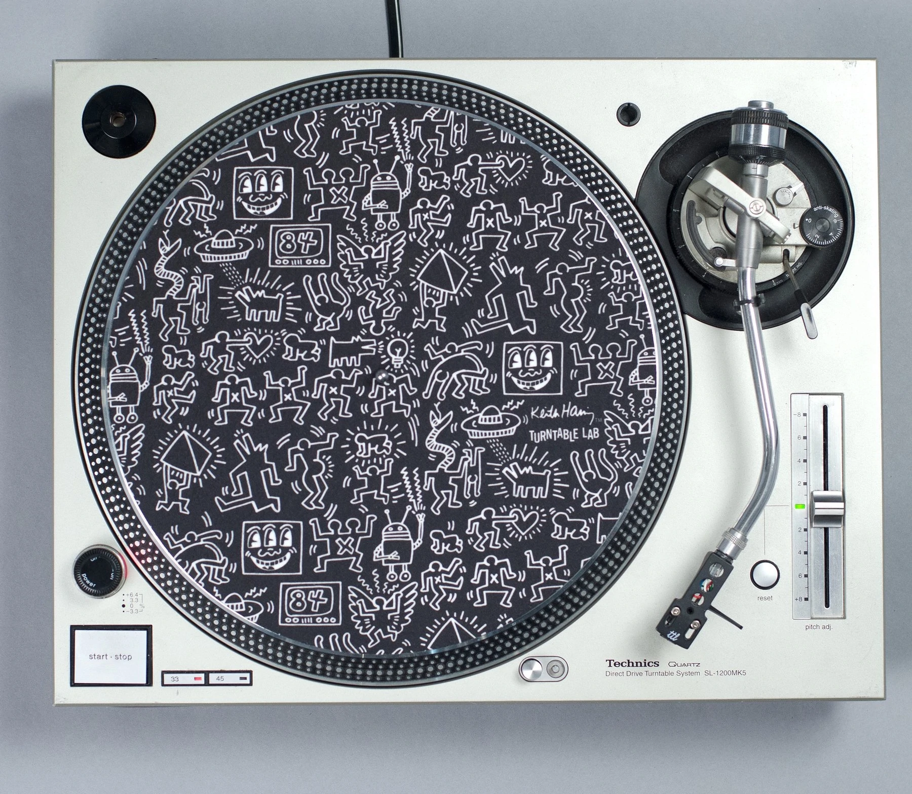 Filmado de cima, um toca-discos com um tapete de vinil Keith Haring