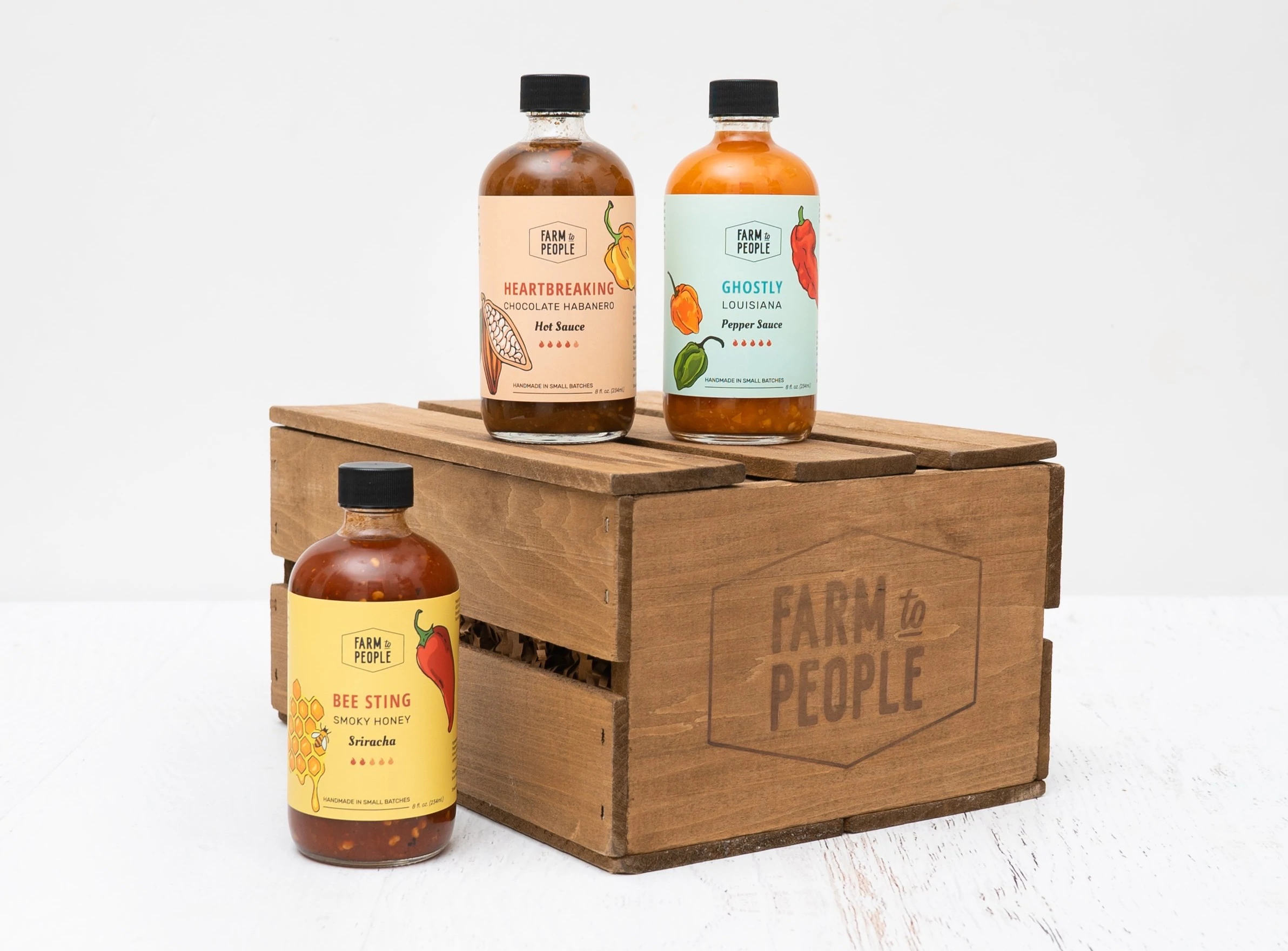 conjunto de presentes farm to People com 3 garrafas de molho picante estilizado em uma caixa de madeira