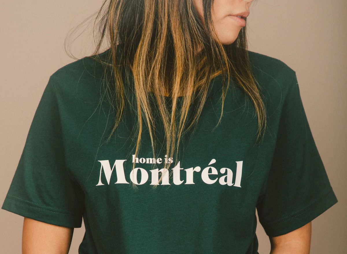 Une femme porte un t-shirt vert sur lequel on peut lire "Home is Montreal"