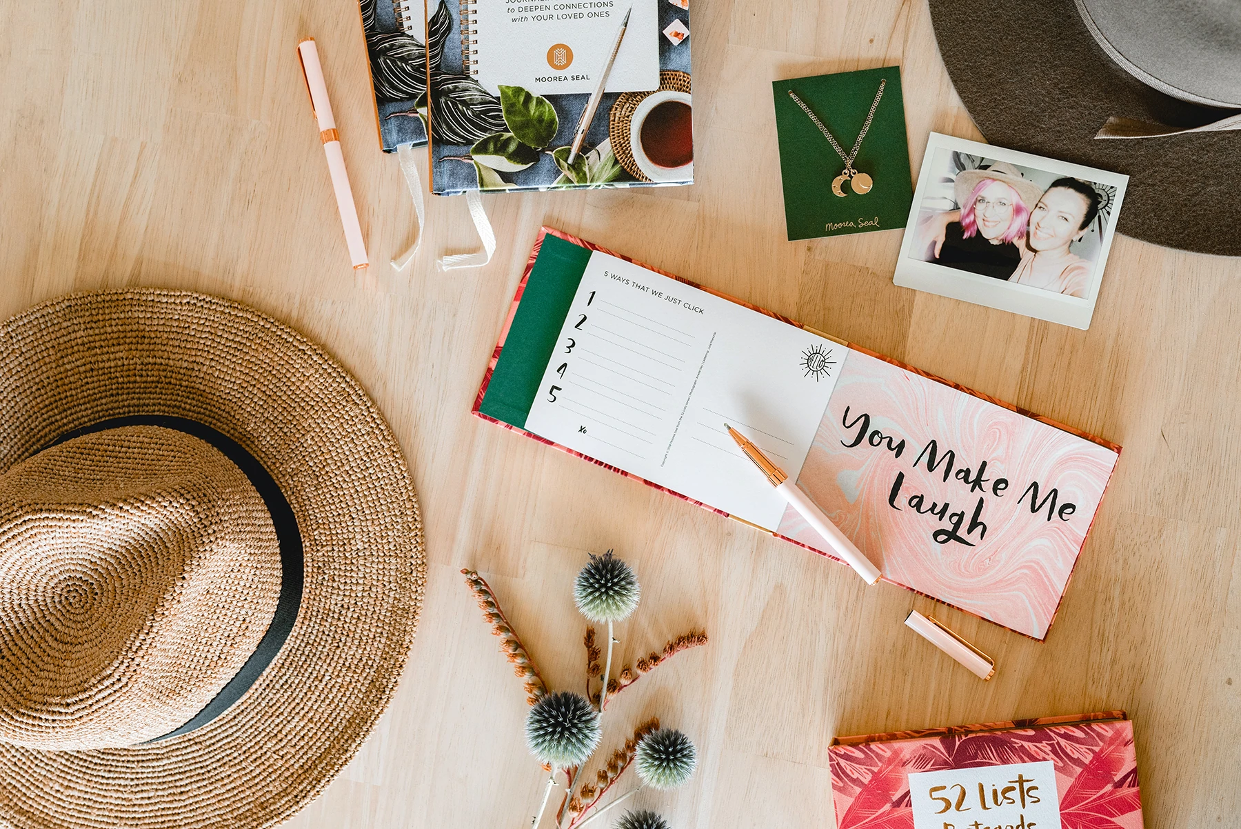 Une photo du dessus d'une table avec des stylos, un carnet, des chapeaux et des bijoux