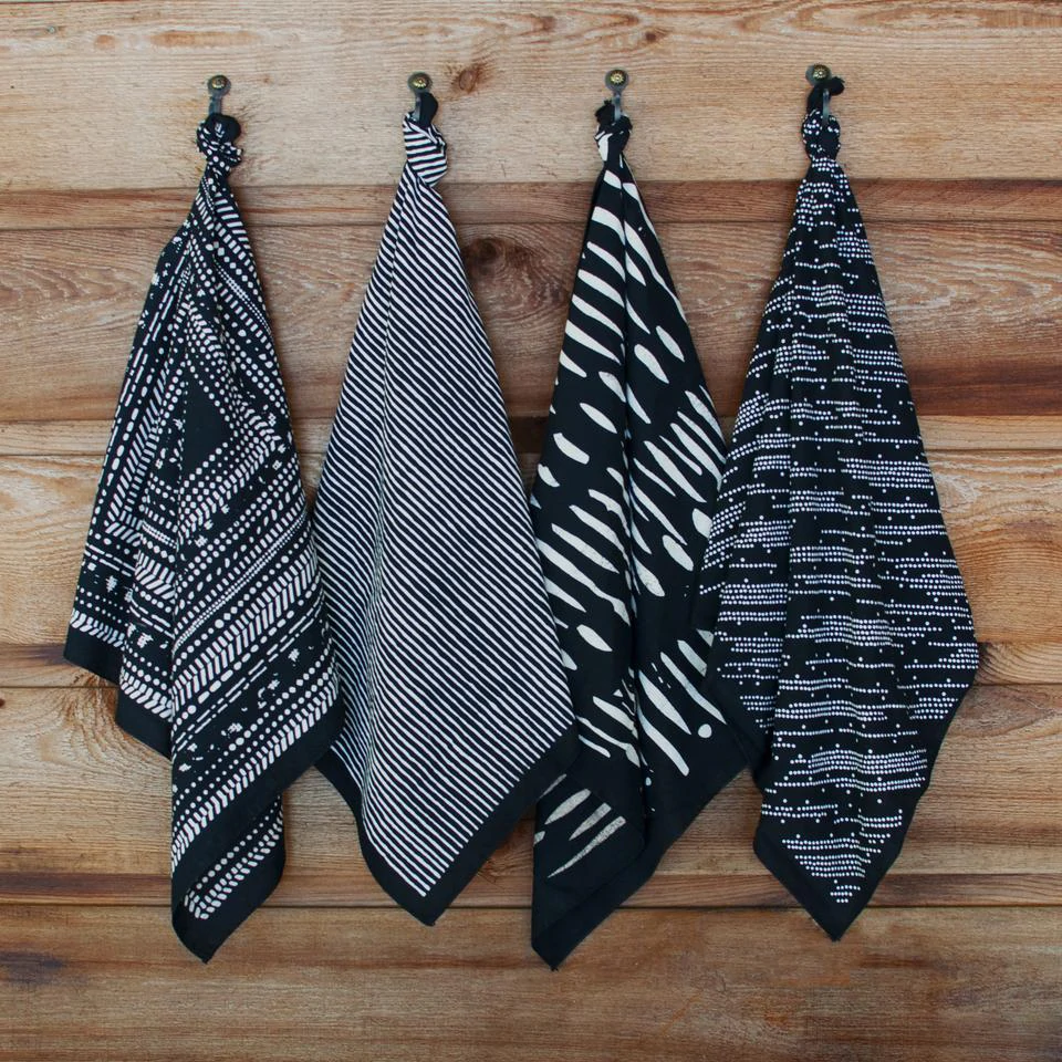 4 bandanas à motifs noirs et blancs sont suspendus contre un mur en bois