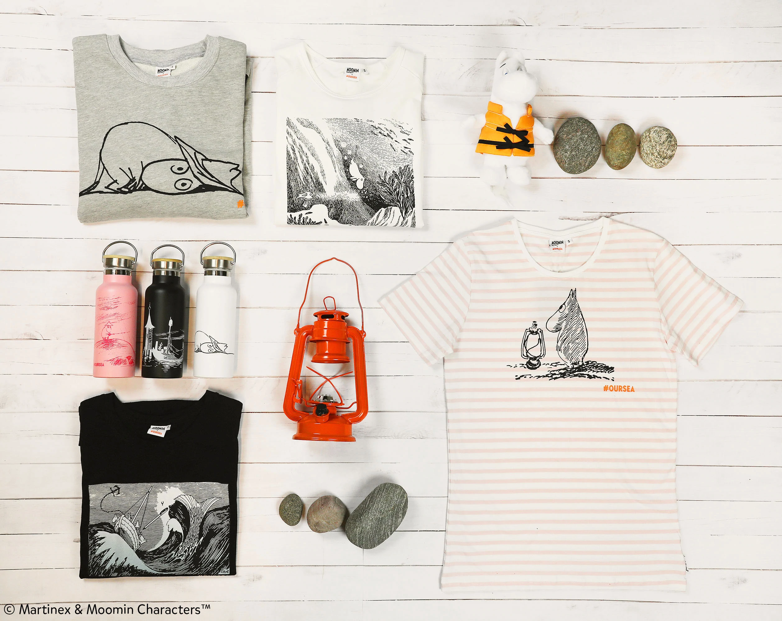 Pilihan merchandise Moomin dalam bentuk flat lay, lengkap dengan t-shirt, botol minum, dan boneka binatang.