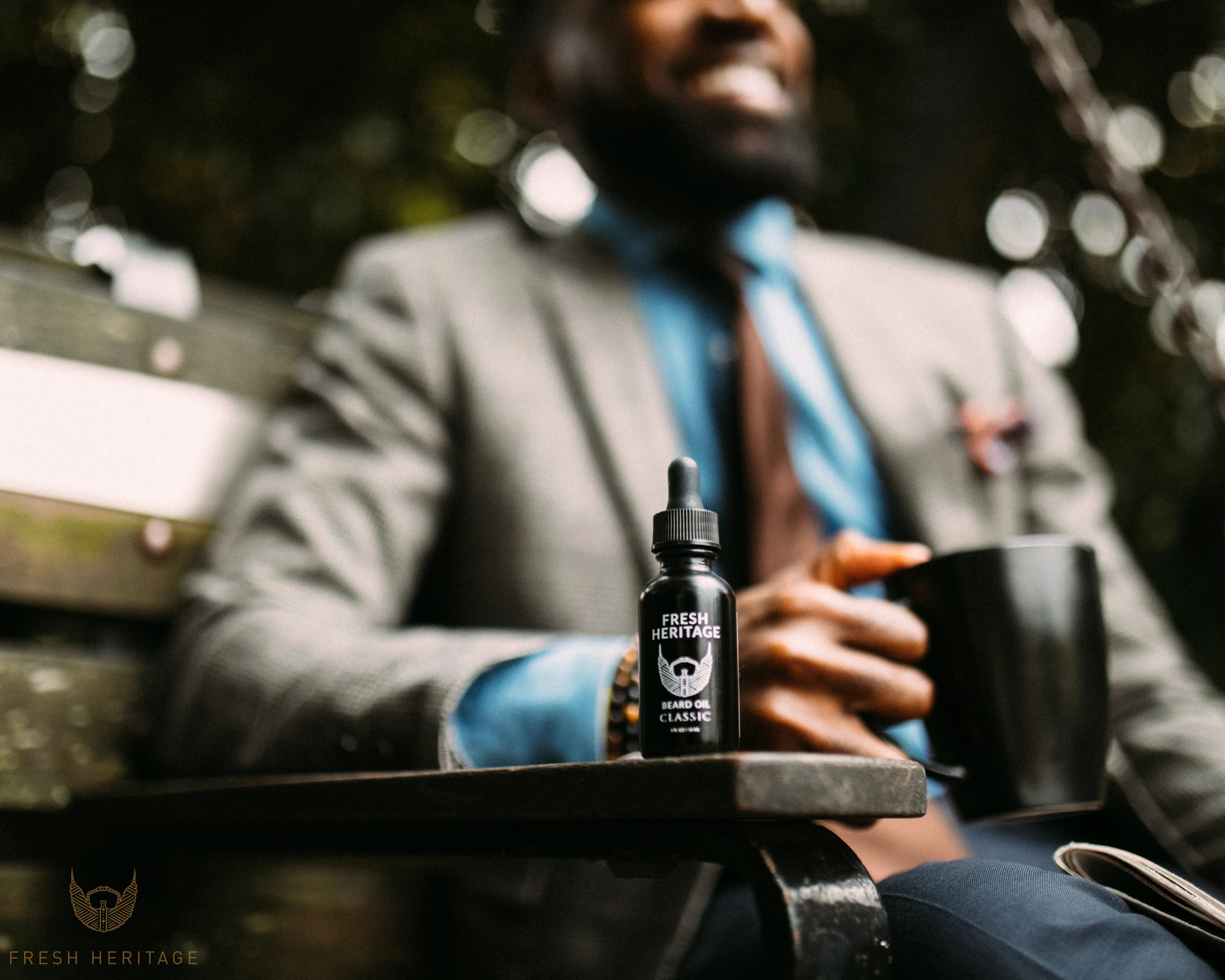 Una modella in abito con un caffè fa da sfondo a una bottiglia di olio da barba di Fresh Heritage.