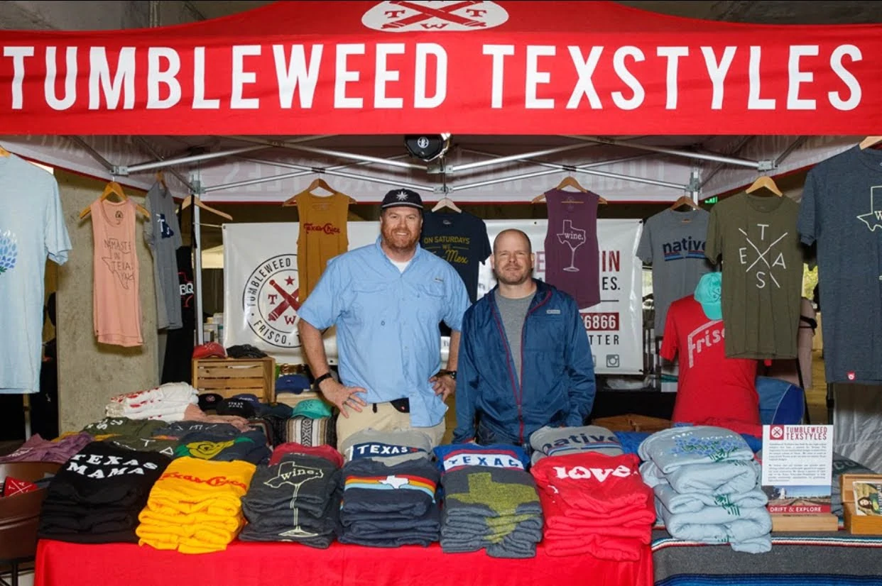 Jeb Matulich e Brian Wysong in piedi all'interno di uno stand di Tumbleweed Texstyles per un evento pop-up che promuove il marchio.