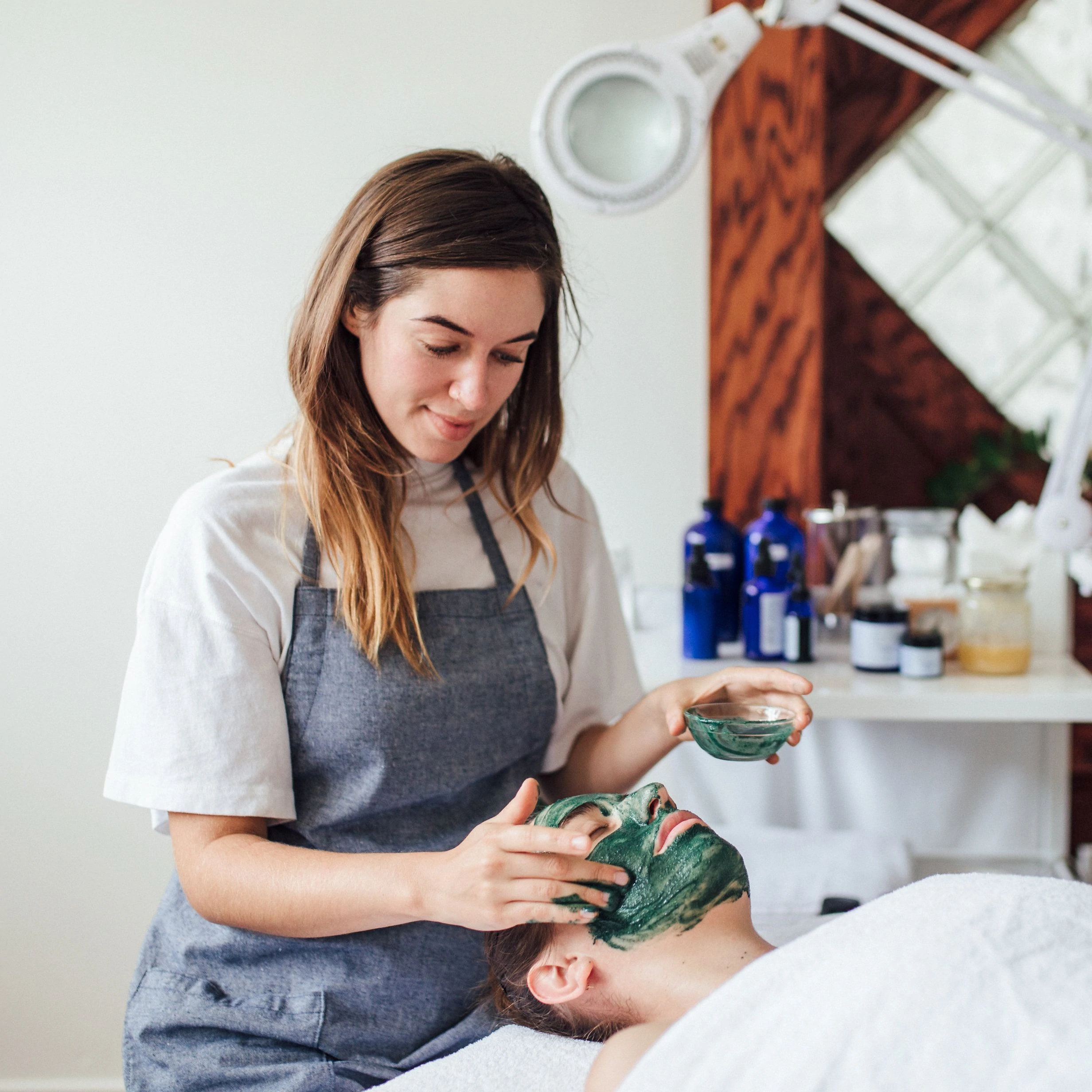 Un'estetista che applica una maschera facciale su un cliente presso il punto vendita di Province Apothecary.