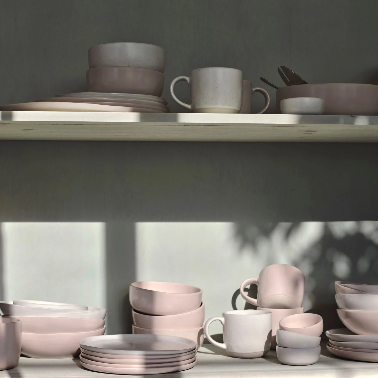 A shelf full of blush pink and speckled white dinnerware from Fable.