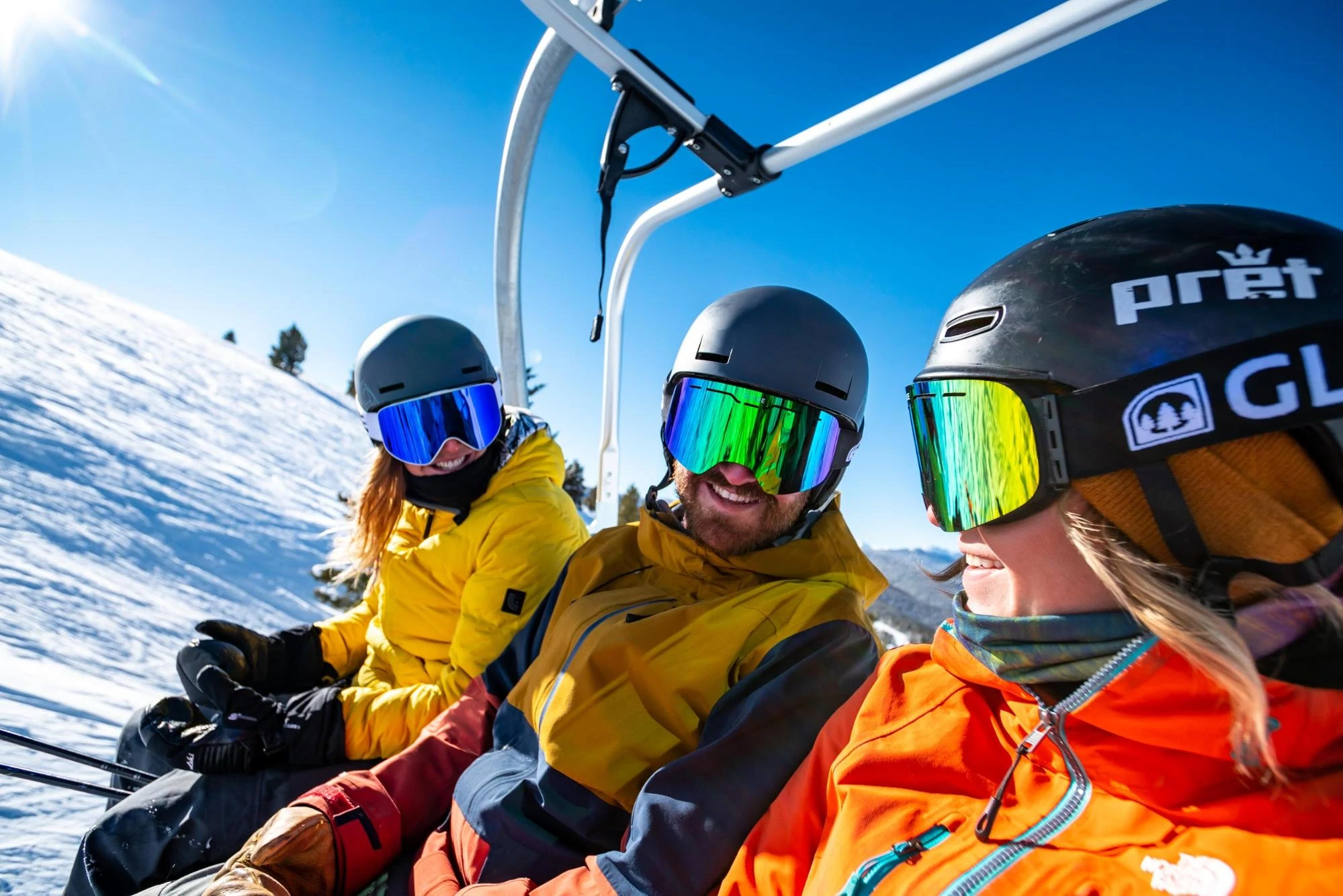 Un gruppo di tre sciatori su una seggiovia indossano tutti gli occhiali di Glade Optics.