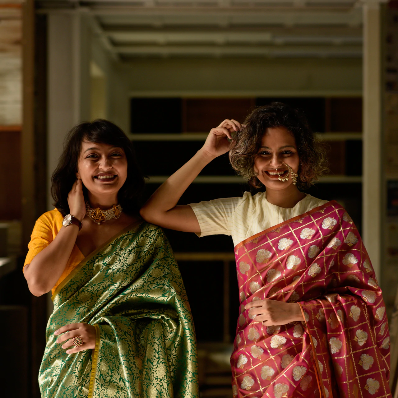 Taniya in a green and gold saree and Sujata in a red and gold saree.