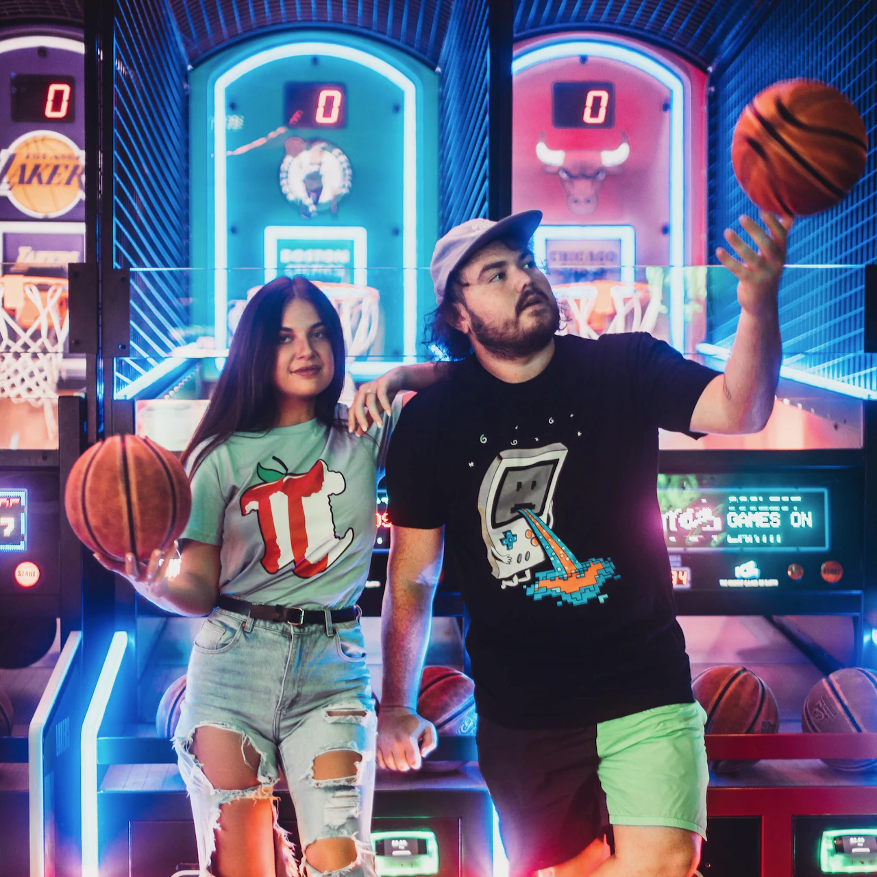 A pair of models in an arcade setting wearing T-shirts designed by Threadheads.