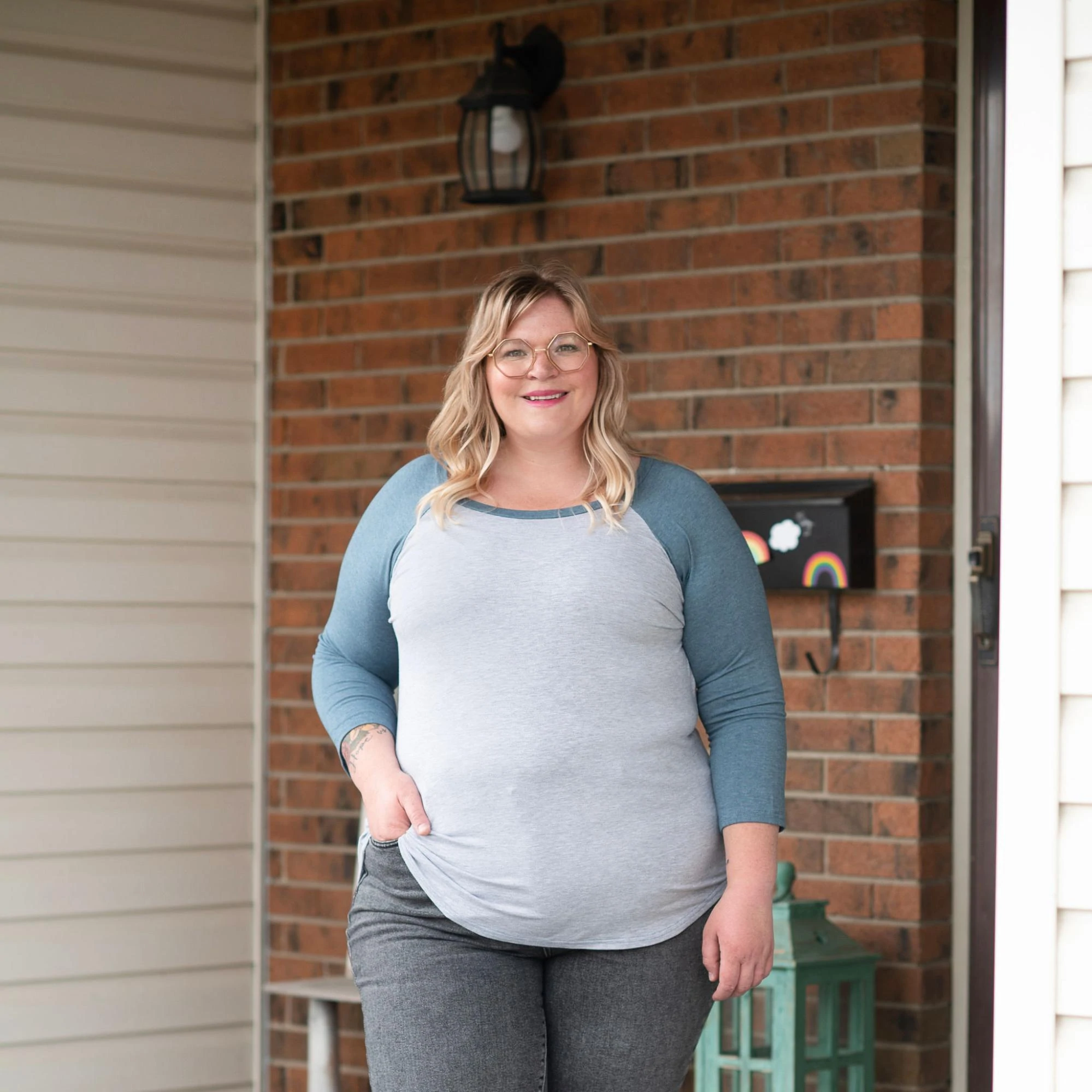 Ein Model auf einer Veranda, das ein Hemd und Jeans von Buttercream Clothing trägt.