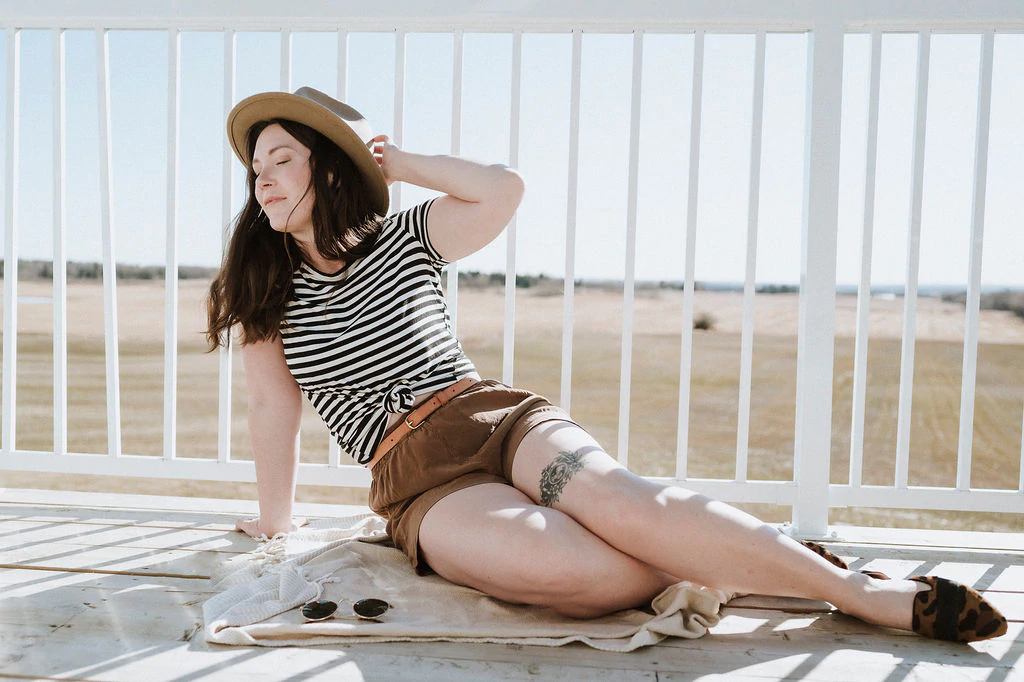 A model on a porch wearing a shirt and shorts from Buttercream Clothing.