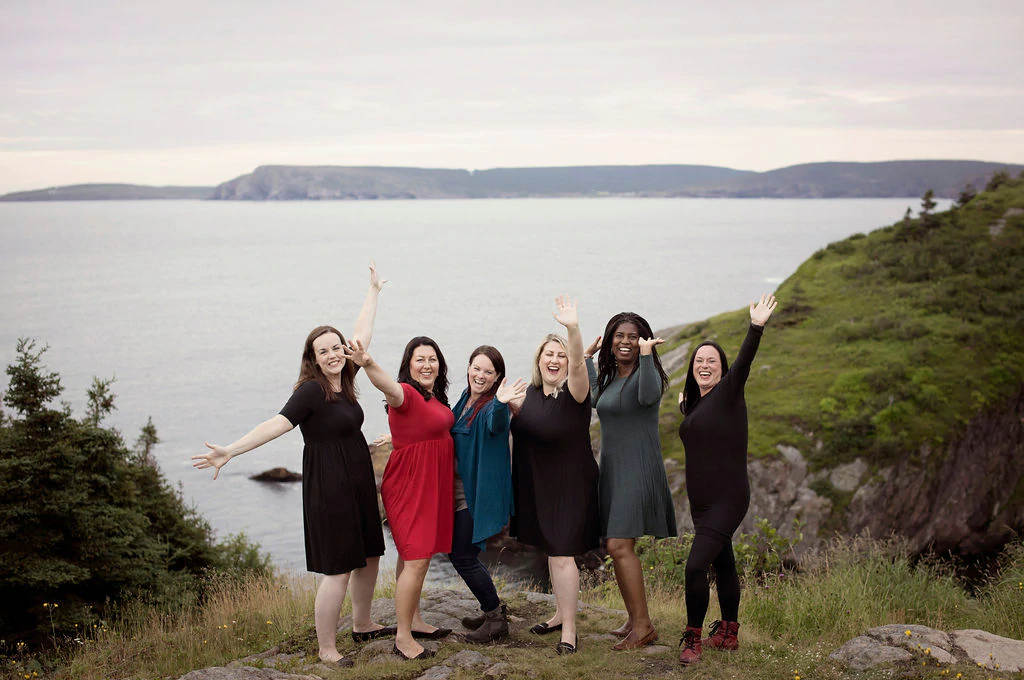 A group of five models wearing clothing from Buttercream Clothing backdropped by cliffs and ocean.