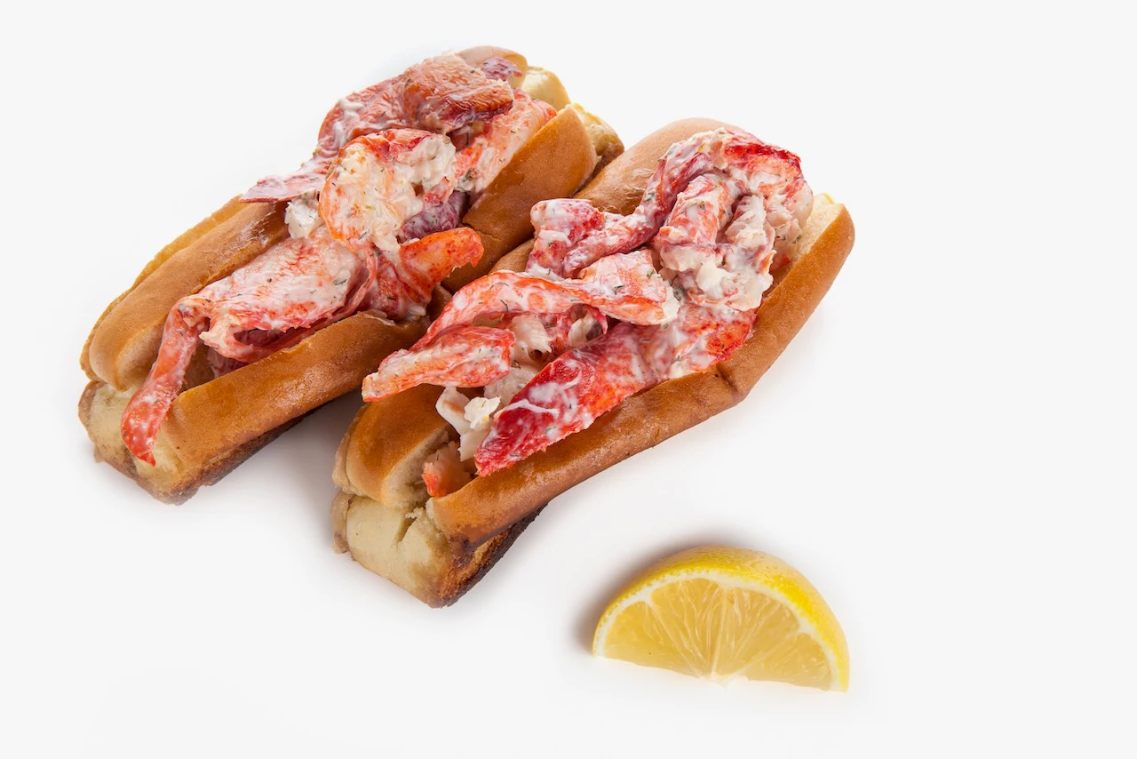 Sepasang lobster roll dan irisan lemon.