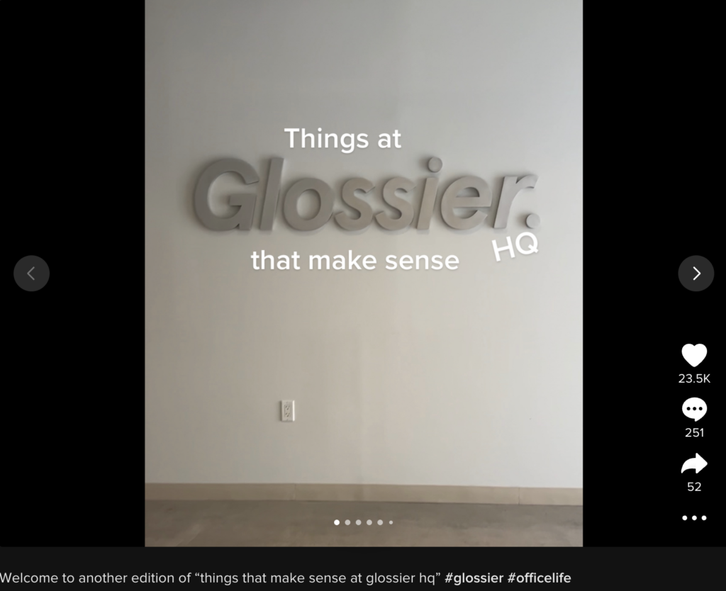 会社の本社で Glossier のサインを表示し、Glossier HQ で意味のあるものを読み取る画面上のテキストを表示する Glossier TikTok。