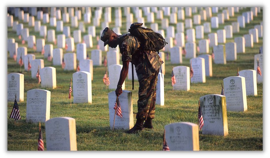 personal militar poniendo la bandera frente a la lápida en el cementerio para el día conmemorativo