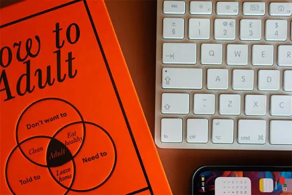 Photo of a book cover, keyboard, and smartphone on a desk.